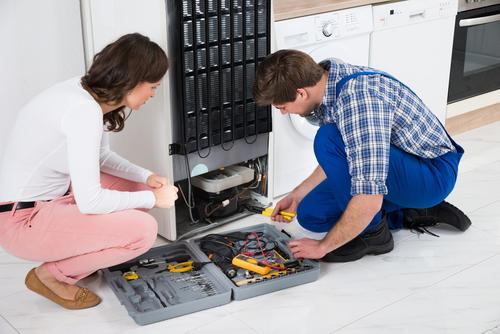 Técnico e cliente consertando geladeira